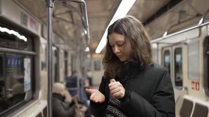 年轻女子在地铁中握住扶手后使用消毒剂