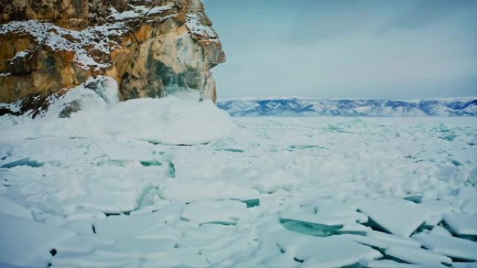 贝加尔湖，飞过破碎的冰，蓝色的雪驼峰。山脊和背景中的黄色岩石。美丽的冬季风景。俄罗斯西伯利亚贝加尔湖