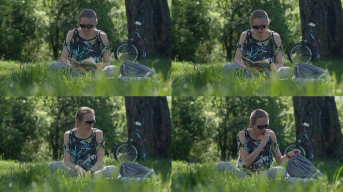 戴着墨镜的女人坐在公园的草地上看书