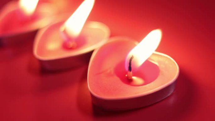 红色燃烧的蜡烛呈心形，火焰燃烧。红色背景上的火舌。情人节，激情，爱情，感情，浪漫的心情概念。2月14