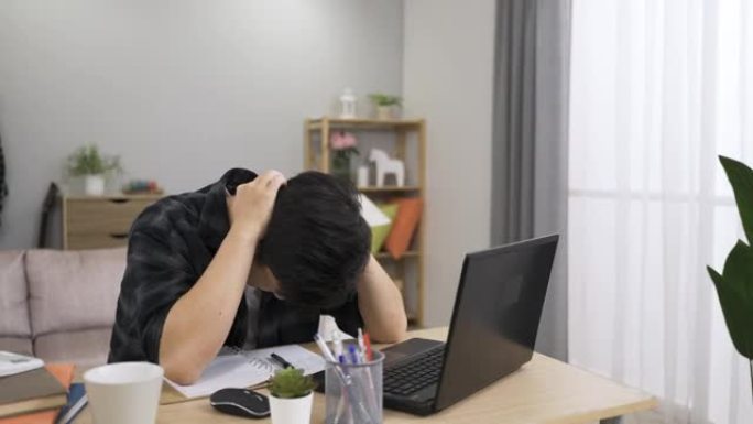 在家里工作的亚洲年轻人在客厅的笔记本电脑上打字报告时大喊大叫，并因数据丢失而情绪崩溃