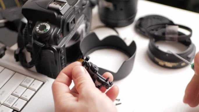 男子修理相机镜头、自动对焦电机、工具。螺栓螺钉