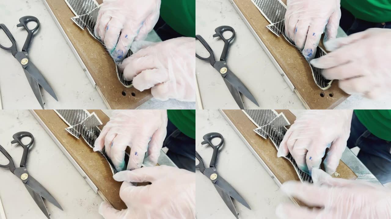 一名防护手套专家在烤盘上铺了一层碳布，并切割，碳纤维条，木材压榨机模具
