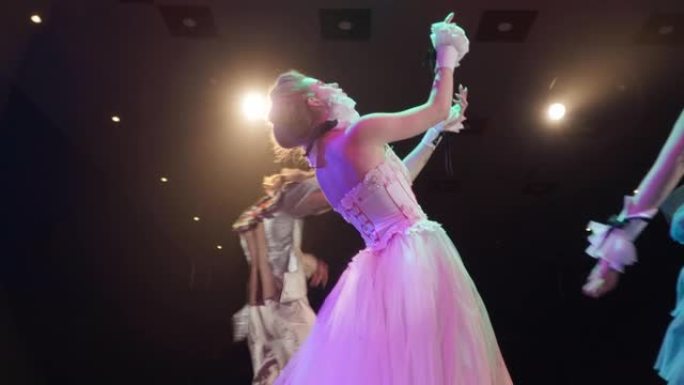 高加索专业女演员慢动作，演员在聚光灯下在舞台上快速跳舞。才华横溢的男女在剧院表演复古风格的现代表演。