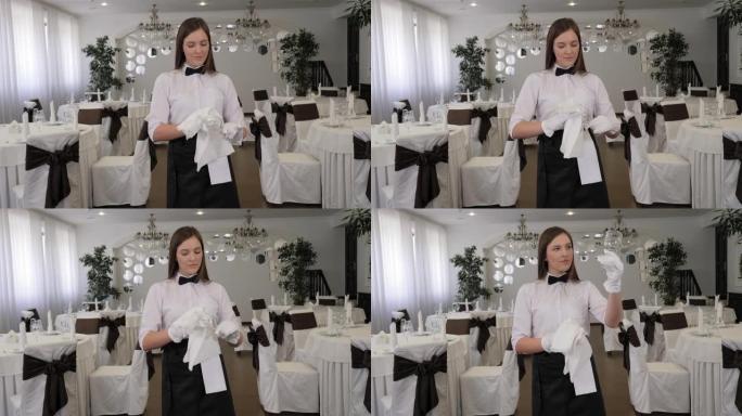 一个年轻的女服务员在一家餐馆用白色餐巾纸擦杯子。