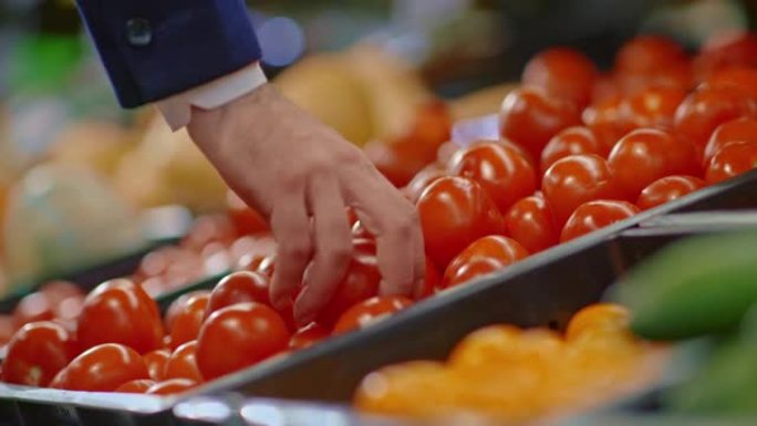 男人在杂货店或市场上拿新鲜成熟的西红柿，用蔬菜，4K，Prores