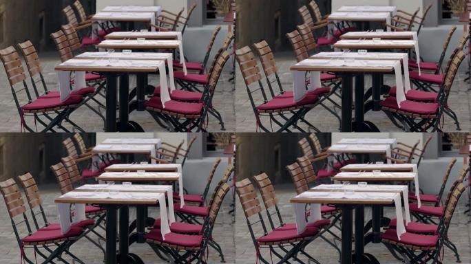 外面的reataurant露台，空木桌，空玻璃烟灰缸，白色食物垫和带红色座垫的椅子，电晕大流行，没有