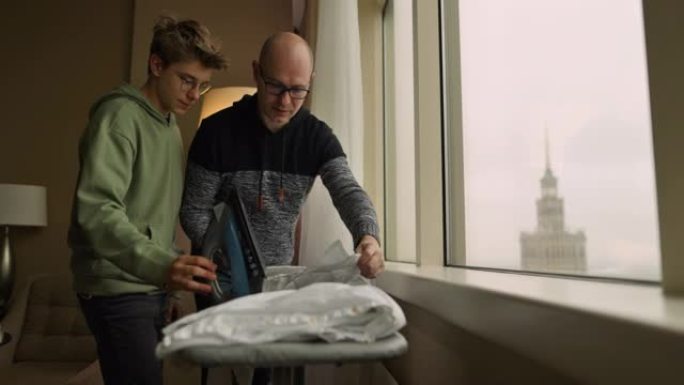 父亲教导并向儿子展示如何熨烫衬衫。