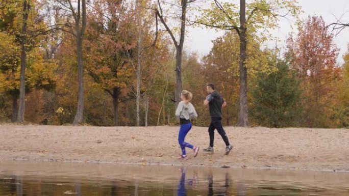 年轻人运动夫妇上午沿湖水线奔跑