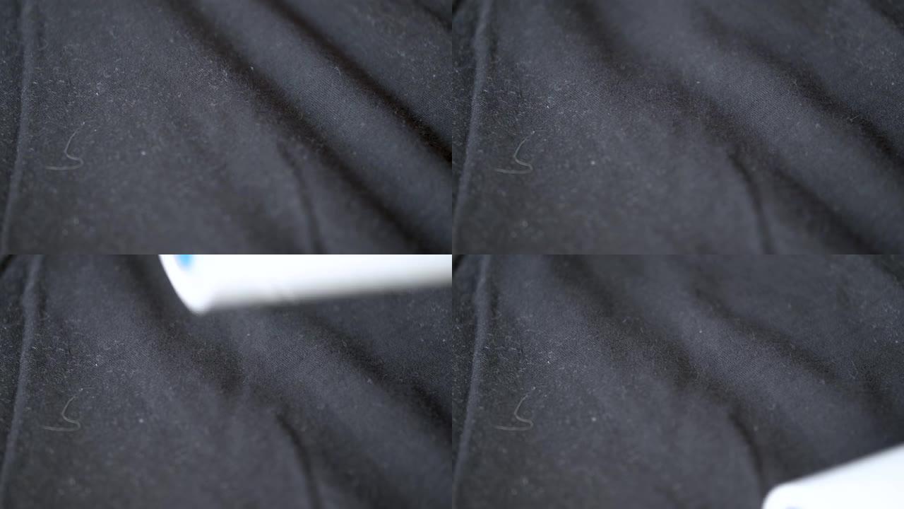 黑色t恤上的粘性棉绒去除剂滚筒的特写镜头。