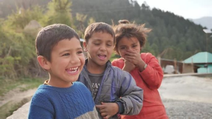 一群快乐可爱的年轻农村小孩看着相机大笑的户外特写