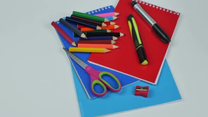 浅色背景上的文具，一套用于绘画的彩色铅笔，两个记号笔，卷笔刀，剪刀，记事本和彩纸。儿童创意办公用品的