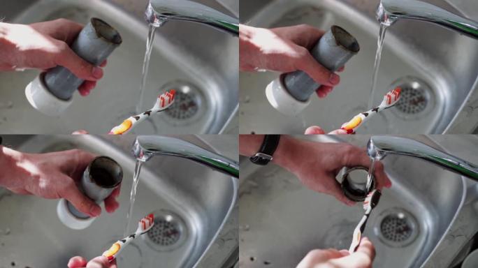 男性水管工的手正在用牙刷清洁虹吸管。