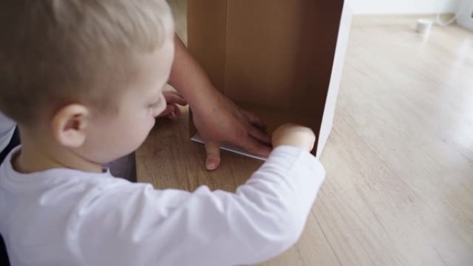 男孩用手收集一个包装纸箱，母亲帮助他