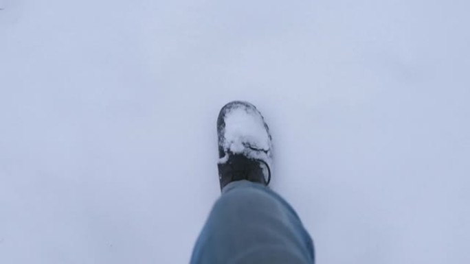穿着蓝色牛仔裤的男人的腿在雪地里行走