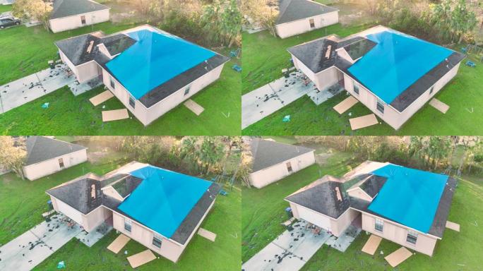 飓风伊恩房屋屋顶上覆盖着蓝色防护篷布的受损鸟瞰图，以防雨水泄漏，直到更换沥青瓦为止