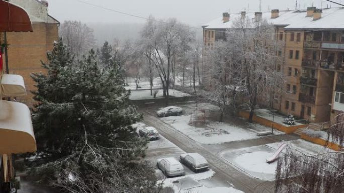 城市降雪。大片白色雪花从多云的天空落下。巴尔干半岛的天气预报。唐楼和树木被雪覆盖。