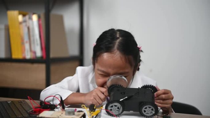 亚洲小女孩在STEM类构建和编码机器人，固定和修理机械玩具车