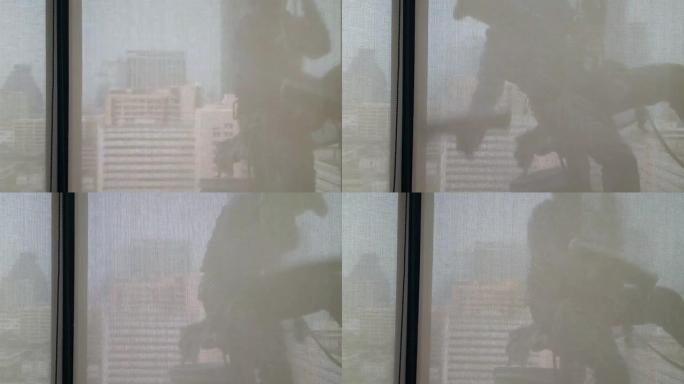 剪影镜头并通过建筑物内部的透明窗帘效果进行拍摄，该人员用擦拭海绵桶的设备清洁高办公楼的窗户，并且存在