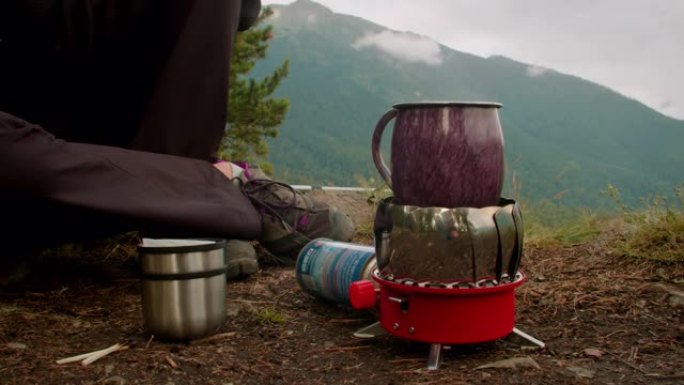 旅行者女人在山上的伯恩户外煮热饮