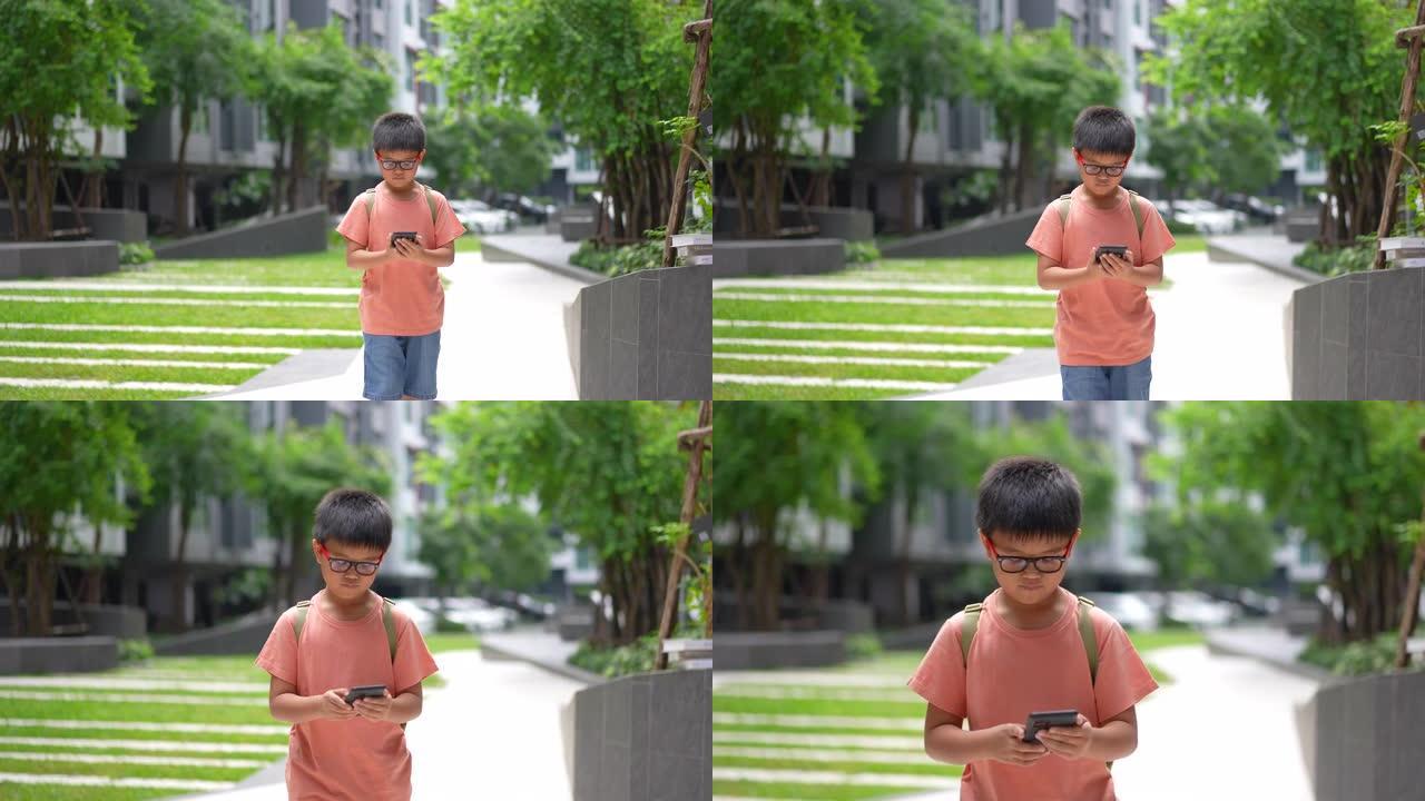 亚洲男孩走路时使用智能手机上网，在日常生活中玩游戏