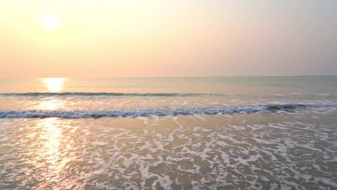 当海浪席卷海滩时，金色的太阳沉入海洋地平线。
