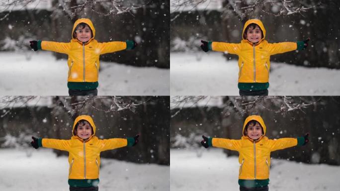 穿着黄色冬装的有趣小男孩在降雪时行走。孩子们的户外冬季活动。