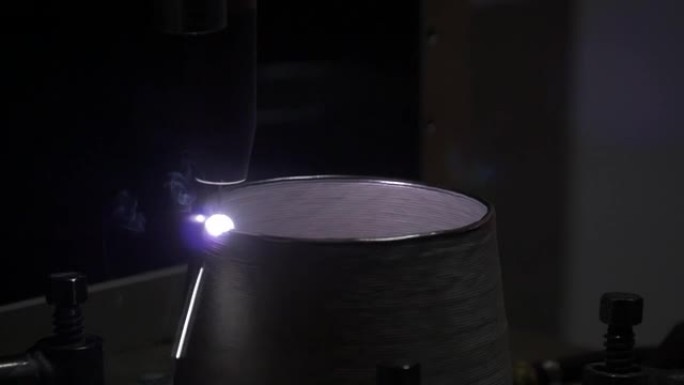 亚麻灯罩上使用的焊接工具的特写镜头，在黑暗中反射紫光