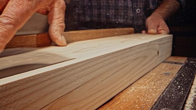 SLO MO DS男性手拿着木梁，同时用台锯切割木梁