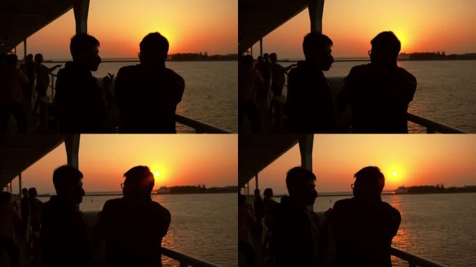 夕阳下在船舷聊天的两名游客