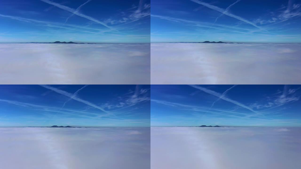 蓝天下的云层的鸟瞰图，背景是山脉，而在雾之间下降