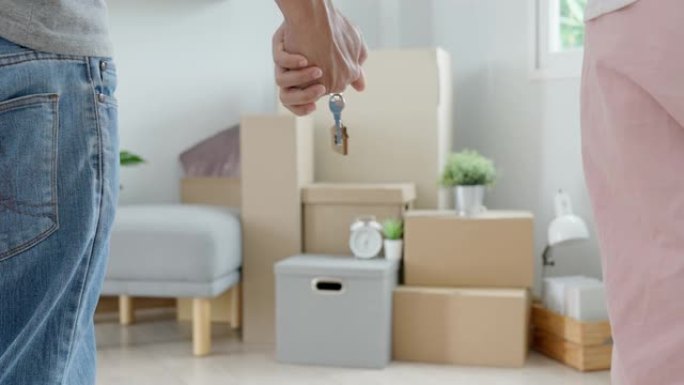 搬家，搬迁。夫妇在新公寓里拿着钥匙扣，房间里是一个装有个人物品和家具的纸板箱。搬进新公寓或公寓