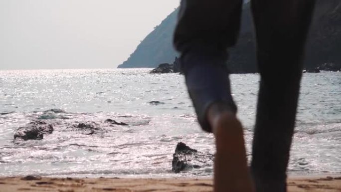 一名印度男性游客在印度果阿走向大海的焦点之腿。选择性地关注男人腿后的大海。自然海滩背景与复制空间。