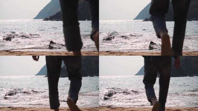 一名印度男性游客在印度果阿走向大海的焦点之腿。选择性地关注男人腿后的大海。自然海滩背景与复制空间。