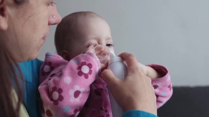 母亲用盐溶液冲洗婴儿的鼻子。