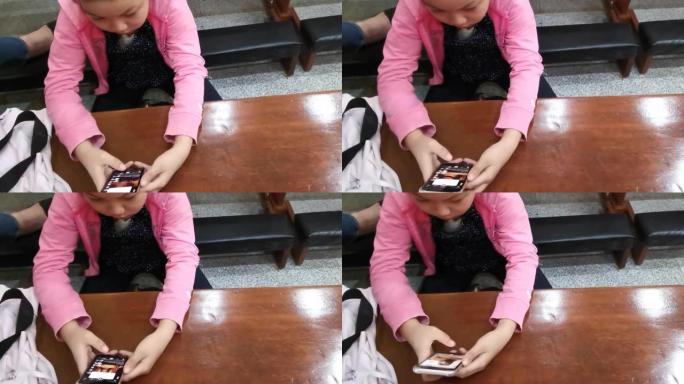 胖乎乎的小女孩拿着移动智能手机，着迷于查看教堂内的社交媒体应用程序内容。