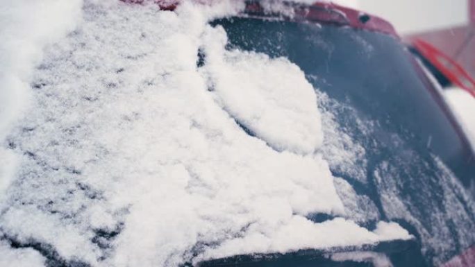 一名男子用刷子清洁一辆冰雪覆盖的汽车。