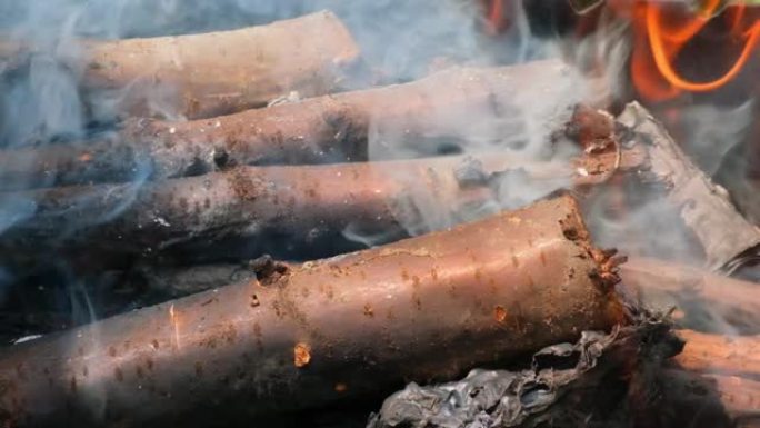 火把木头变成木炭。炭在明亮的火中。木柴，原木，煤在烤架上燃烧。木质原木上生动的火焰的美丽慢动作