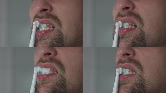 用超声波牙刷清洁牙齿的人的特写。男性用电牙刷刷牙。主题口腔健康和牙齿卫生。浴室里的早上卫生程序。