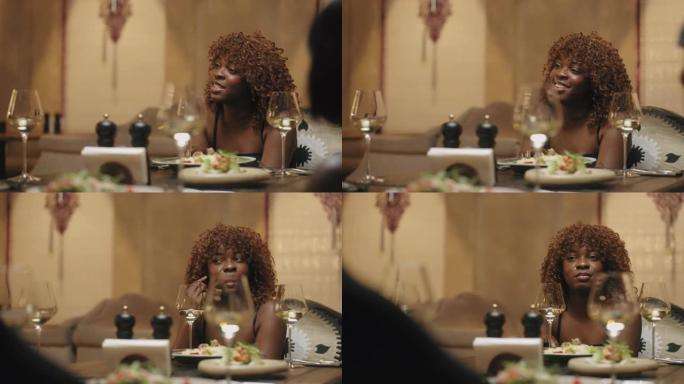 黑人妇女在餐厅的家庭晚餐中，周年纪念日与亲朋好友会面