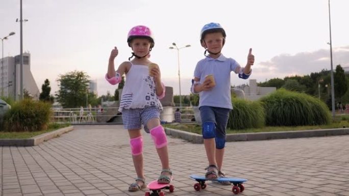 戴着滑板头盔的有趣男孩和女孩在夏季公园吃冰淇淋。