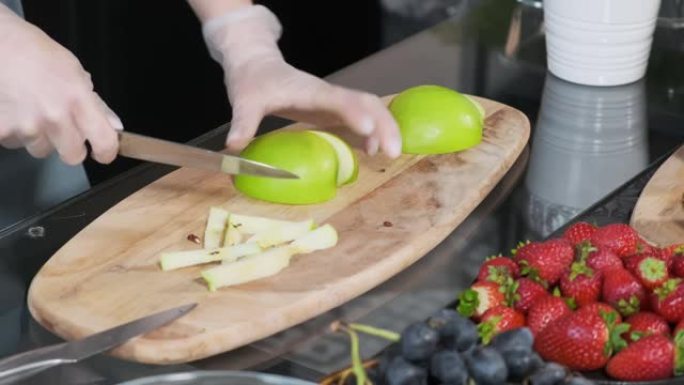 年轻女子在厨房的木板上切一个新鲜的青苹果。健康食品概念
