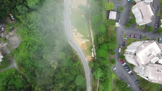 汽车沿着分隔居民楼和森林的道路行驶的航拍视频
