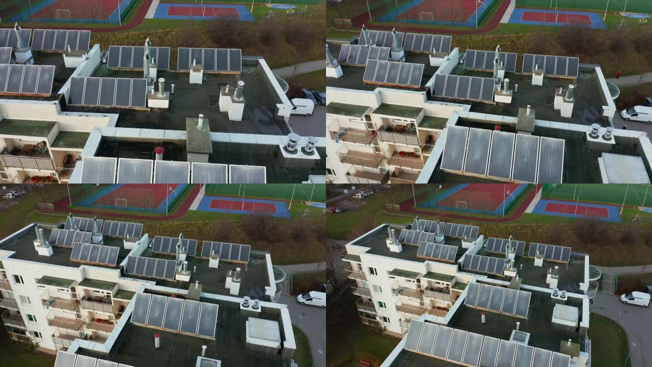 无人机在一栋居民楼的屋顶上拍摄，上面装有太阳能电池板。屋顶上的光伏太阳能电池板接收来自太阳的清洁能源