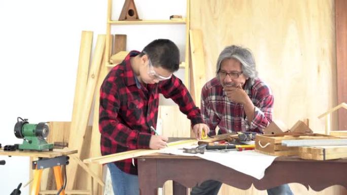 亚洲青少年男孩帮助祖父加工木制品，青少年男孩采取措施制作玩具或木制工艺品，木工父亲培训，教儿子使用工