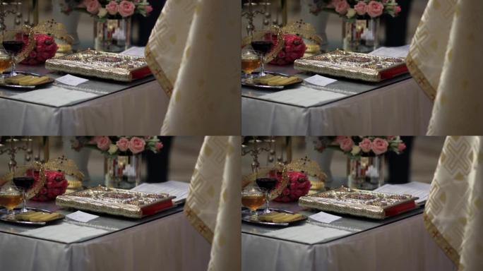 在牧师面前的桌子上是圣书，王冠新郎和传统的装有葡萄酒和威化饼的托盘