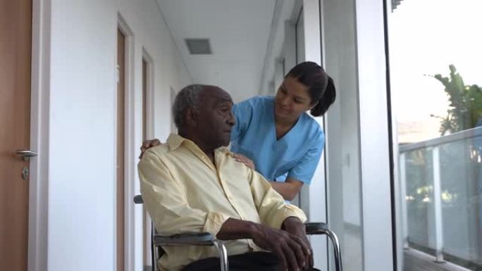 有爱心的护士试图在辅助生活设施的轮椅上安慰黑人高级患者