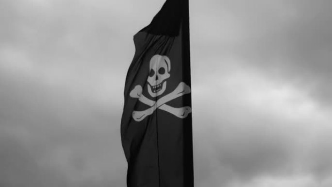 在多云的天空上挥舞着骷髅的海盗旗