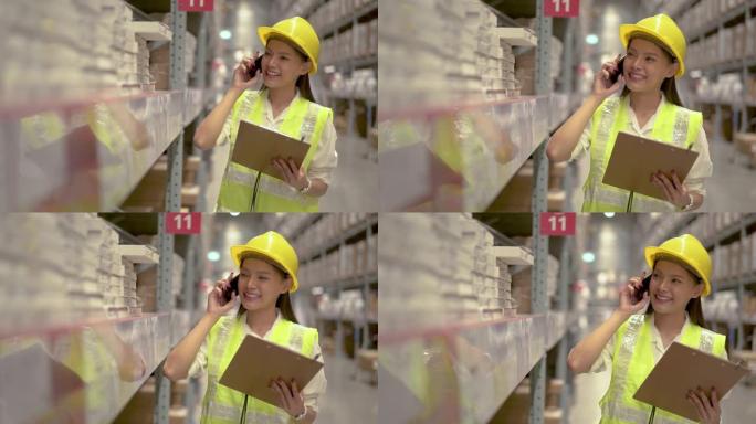 穿着头盔和制服的亚洲妇女在手机上聊天，在配送仓库工厂讨论货架上的库存产品库存数量。物流业务运输和交付
