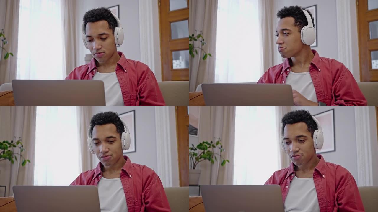 迷人的非洲裔美国年轻人在笔记本电脑上工作，用耳机听音乐